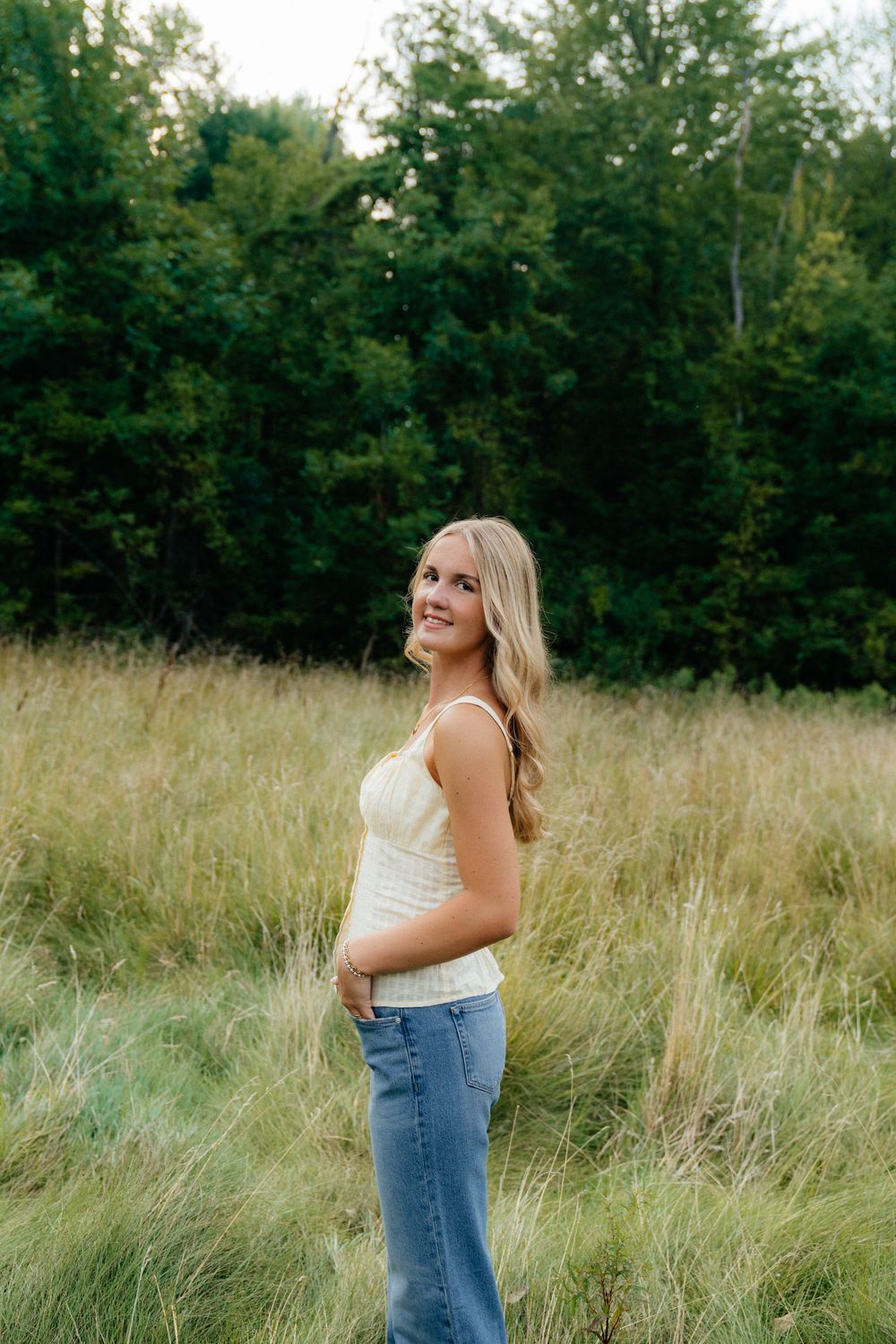 Casual summer outfit styled with jeans and white top against a natural meadow backdrop.