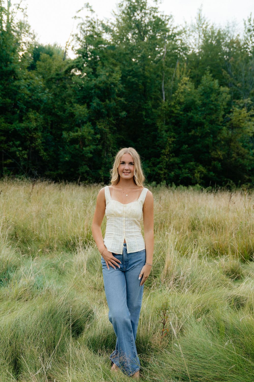 Relaxed summer fashion shoot in a natural meadow setting with denim and white top.
