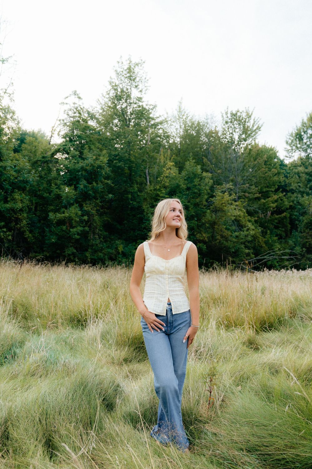 Casual summer fashion photography in a wild grass field with forest backdrop.