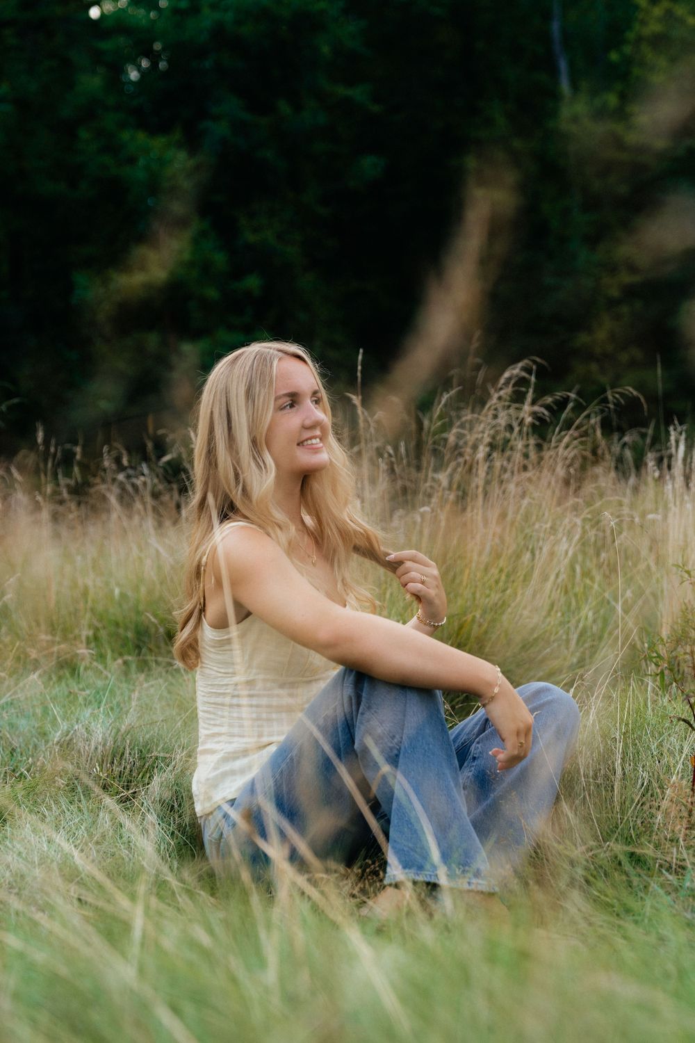 Candid lifestyle photography in tall grass with natural lighting and forest background.