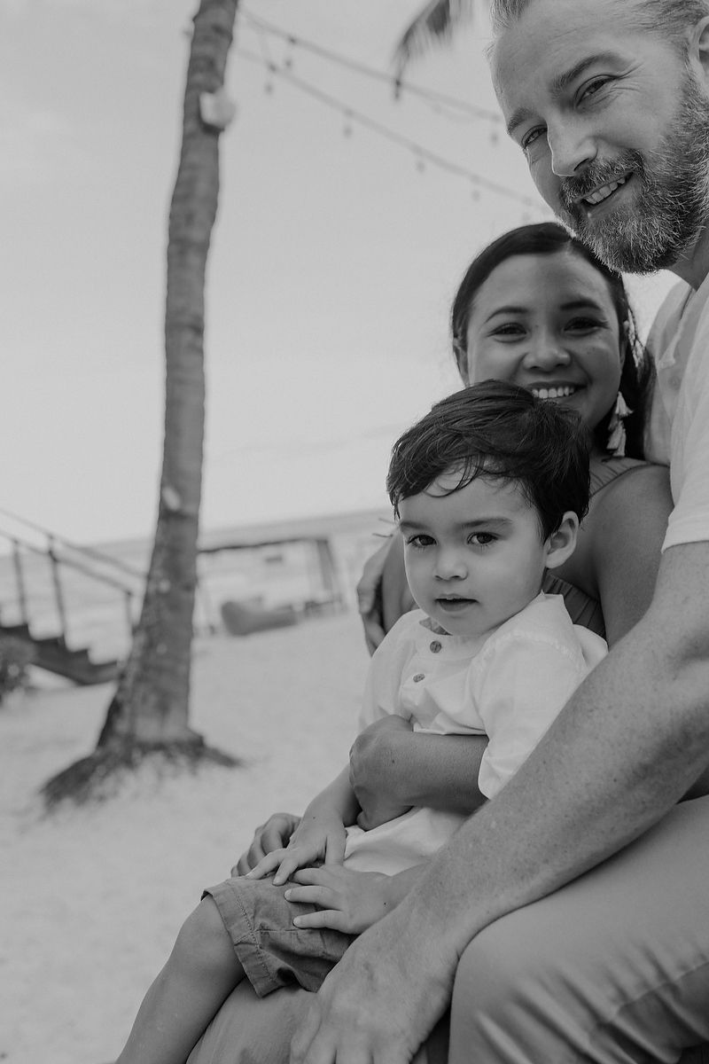 Black and white portrait of father embracing son during editorial family session in Tulum.
