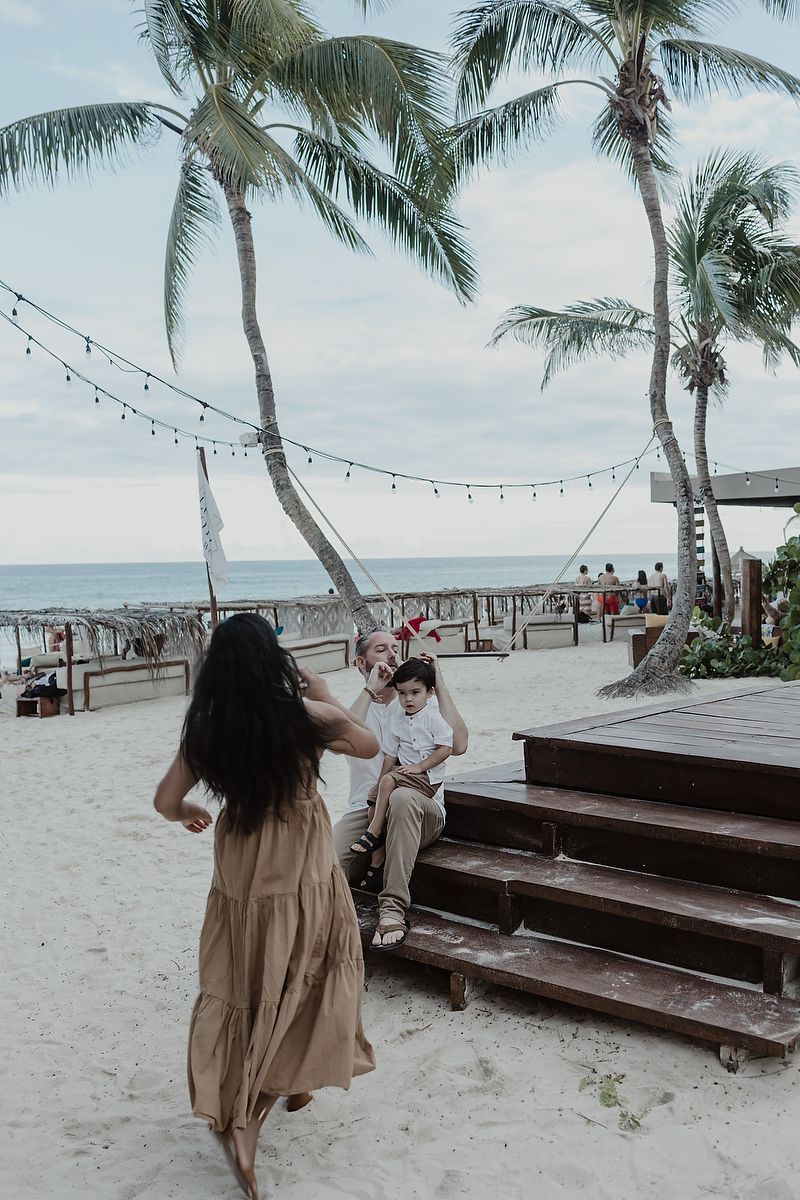 Mother walking by palm trees at La Zebra Hotel during family vacation photoshoot in Tulum.