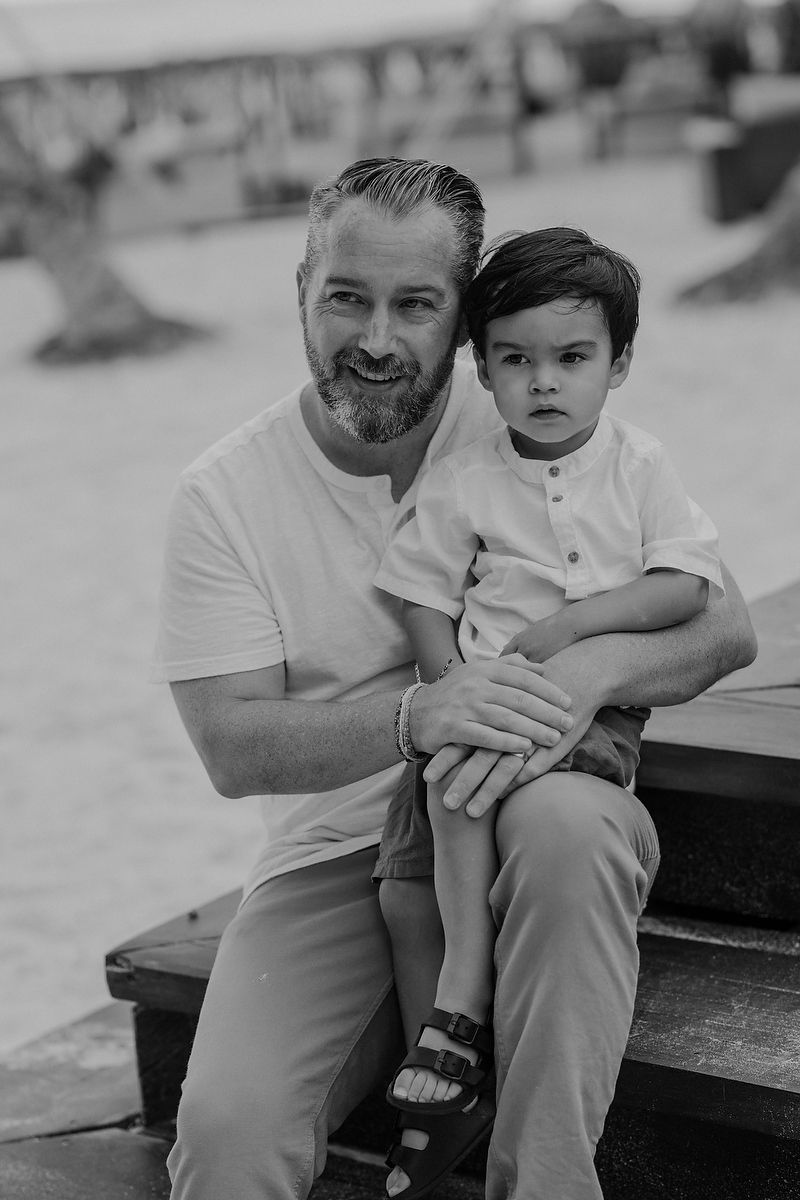 Father holding young son on the beach at La Zebra Hotel, Riviera Maya family photoshoot.