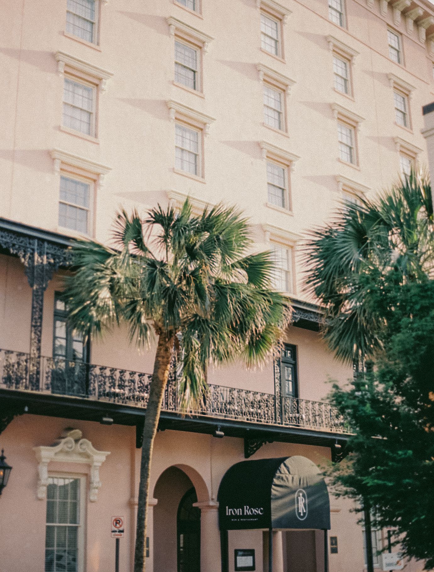 A pink historic hotel building with palm trees and wrought iron balconies.