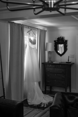 A black and white photo series showing a wedding dress hanging in different angles and rooms of a house.