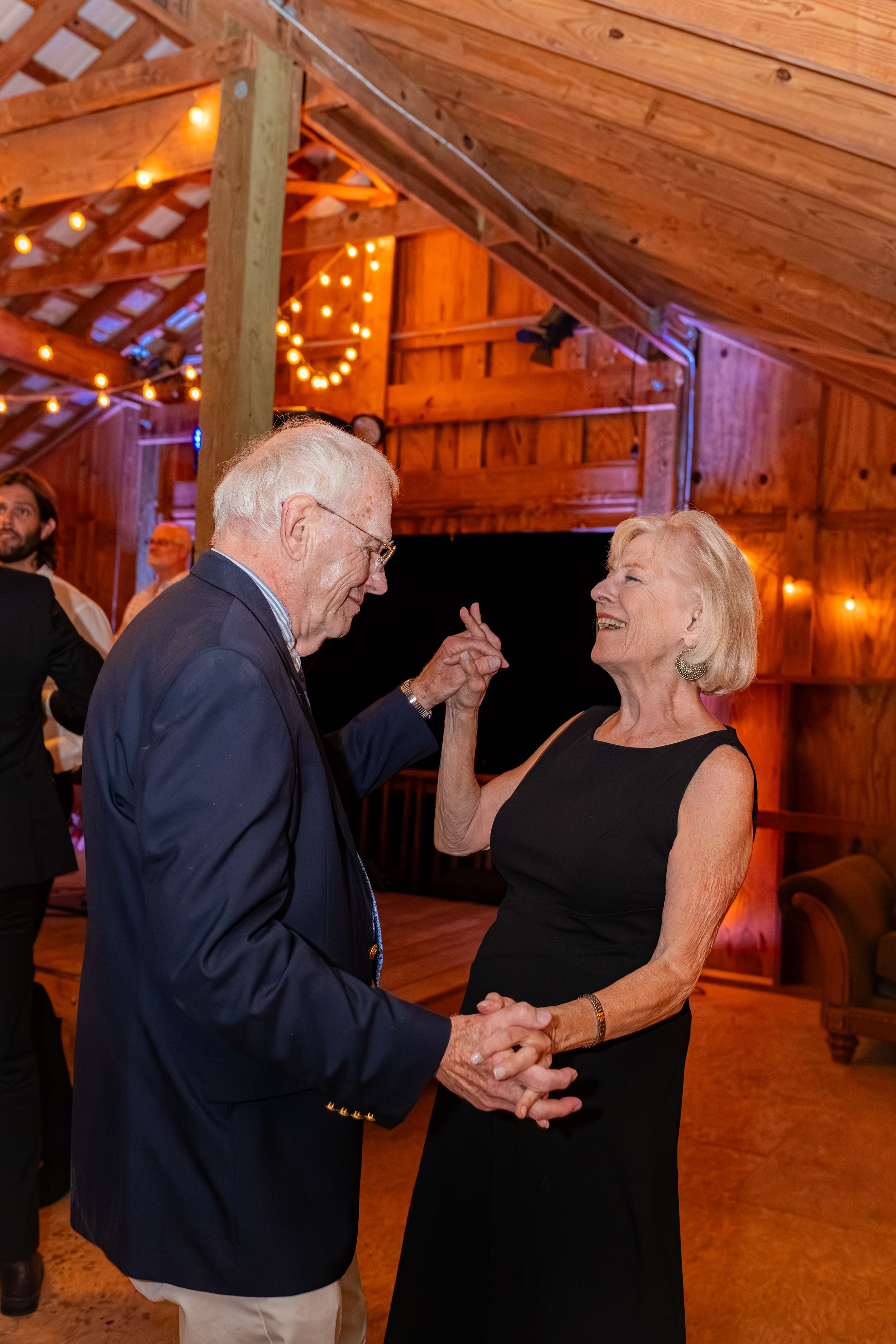 Sequence of dance photos showing a couple enjoying a lively moment together in a rustic barn with string lights.