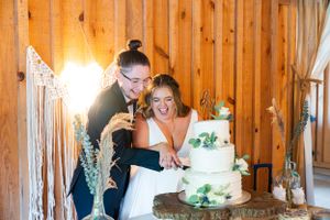 A couple cuts their white wedding cake together in a rustic wooden venue.