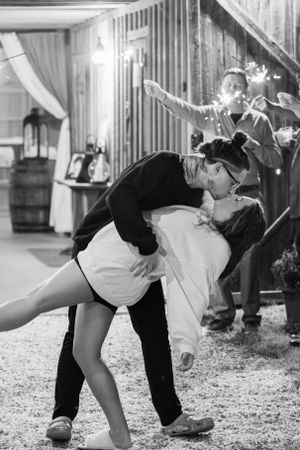 A dramatic dip dance move captured in black and white at an outdoor wedding celebration.