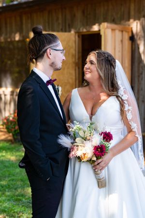 A romantic wedding portrait of a couple with a beautiful bouquet of flowers in front of a rustic barn.