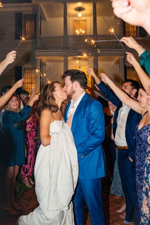 A couple shares a kiss under sparklers during their wedding night send-off.
