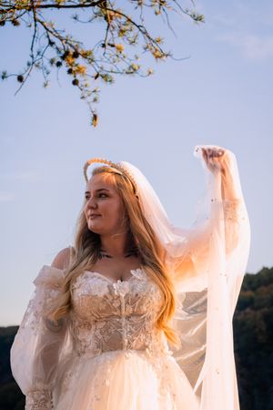 Ethereal bride in flowing dress poses against autumn mountain backdrop.