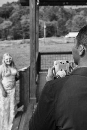 A photographer captures a joyful moment during a photo session on a rustic wooden deck.