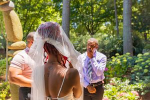 Wedding guests gathered in a sunlit garden setting during an outdoor summer celebration.