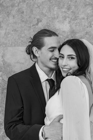 Intimate black and white wedding portrait against a textured backdrop.