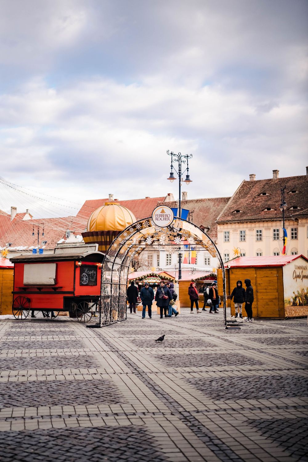 Traditional Christmas market stalls line a cobblestone square in front of historic buildings.