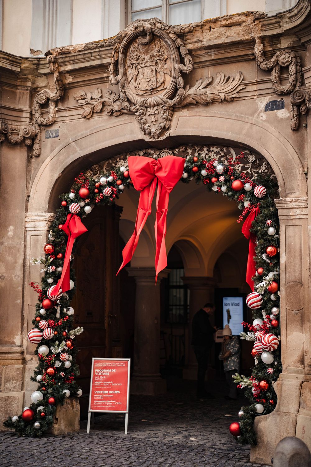 Ornate stone archways decorated with Christmas garlands, ornaments and red bows.