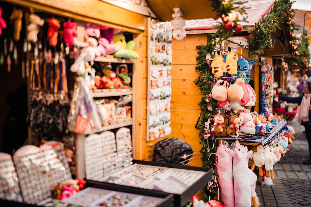Wooden market stall displaying colorful Christmas ornaments and decorative items at a holiday market.