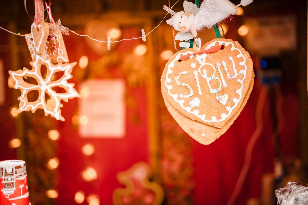 Illuminated gingerbread heart and snowflake ornaments hanging at a Christmas market.