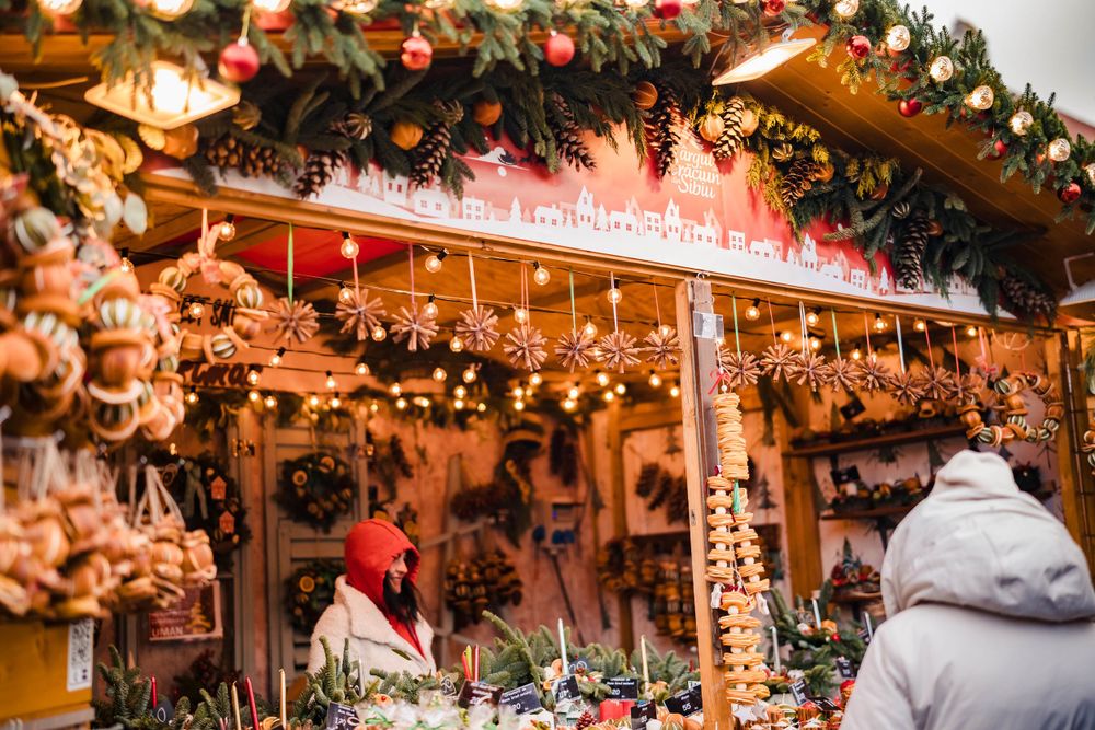 Warmly lit Christmas market stall decorated with evergreen garlands and twinkling lights.