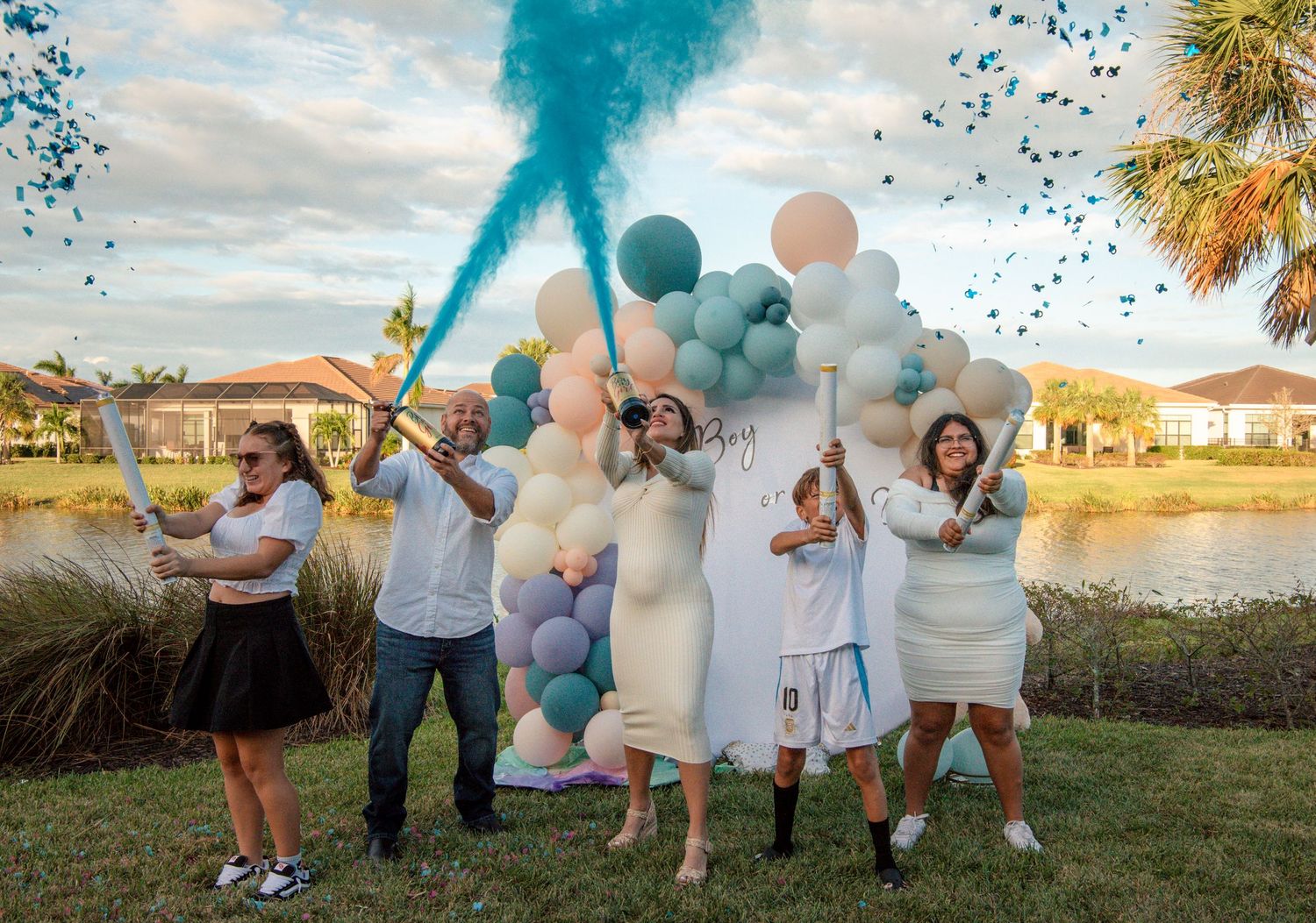 Group celebration with blue smoke bombs and balloons in an outdoor backyard setting.