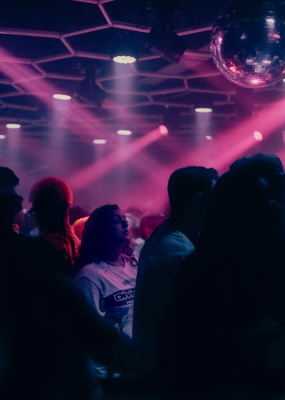Club atmosphere with lights shining down, specifically on one person in the moment