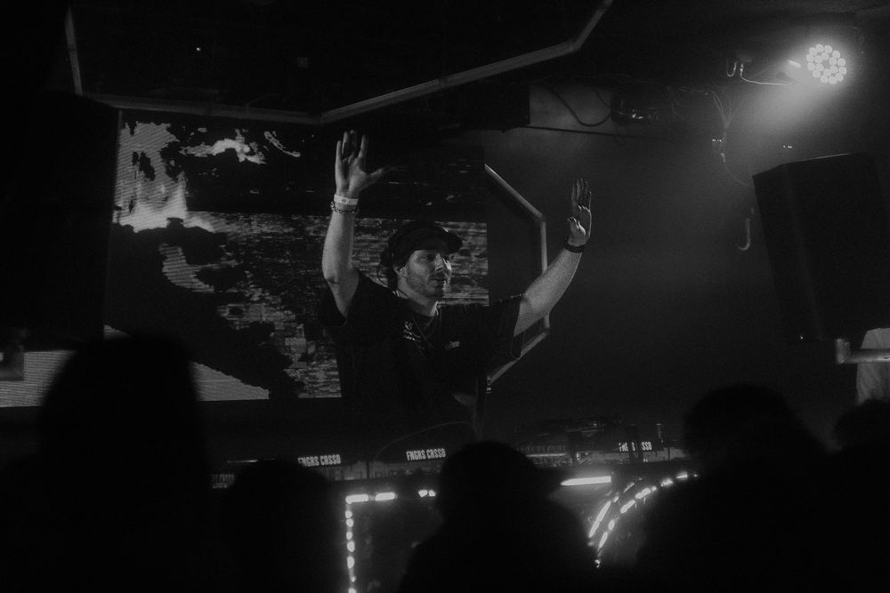 DJ with hands raised during live set in a club