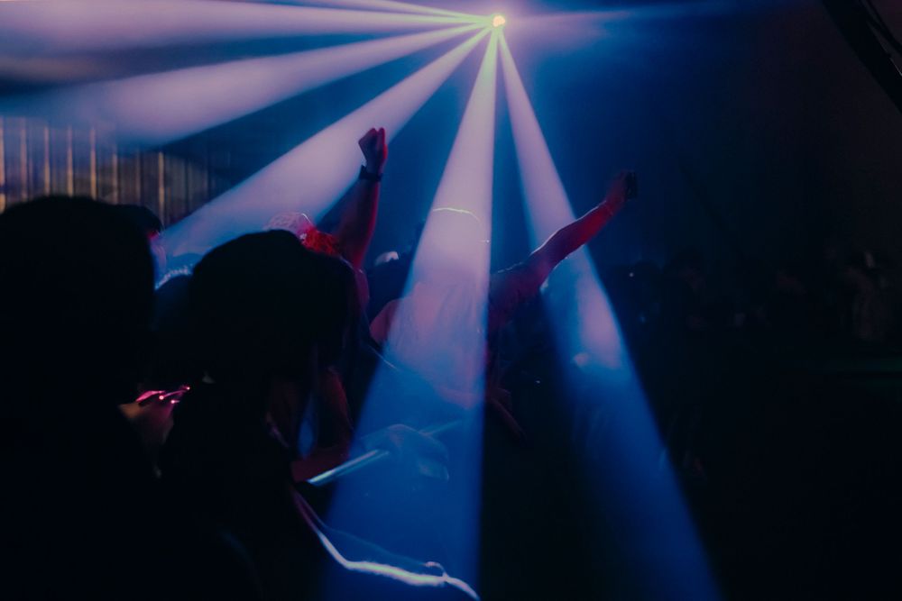 Lights shining on the crowd at a music festival, hands in the air