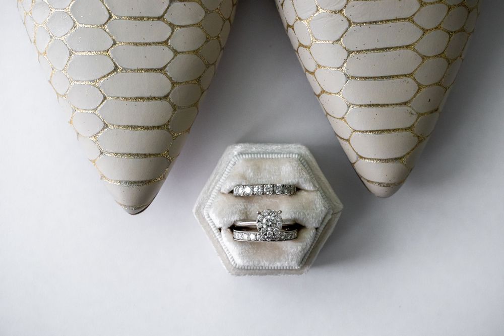 Wedding shoes and hexagonal ring box arranged on white background.