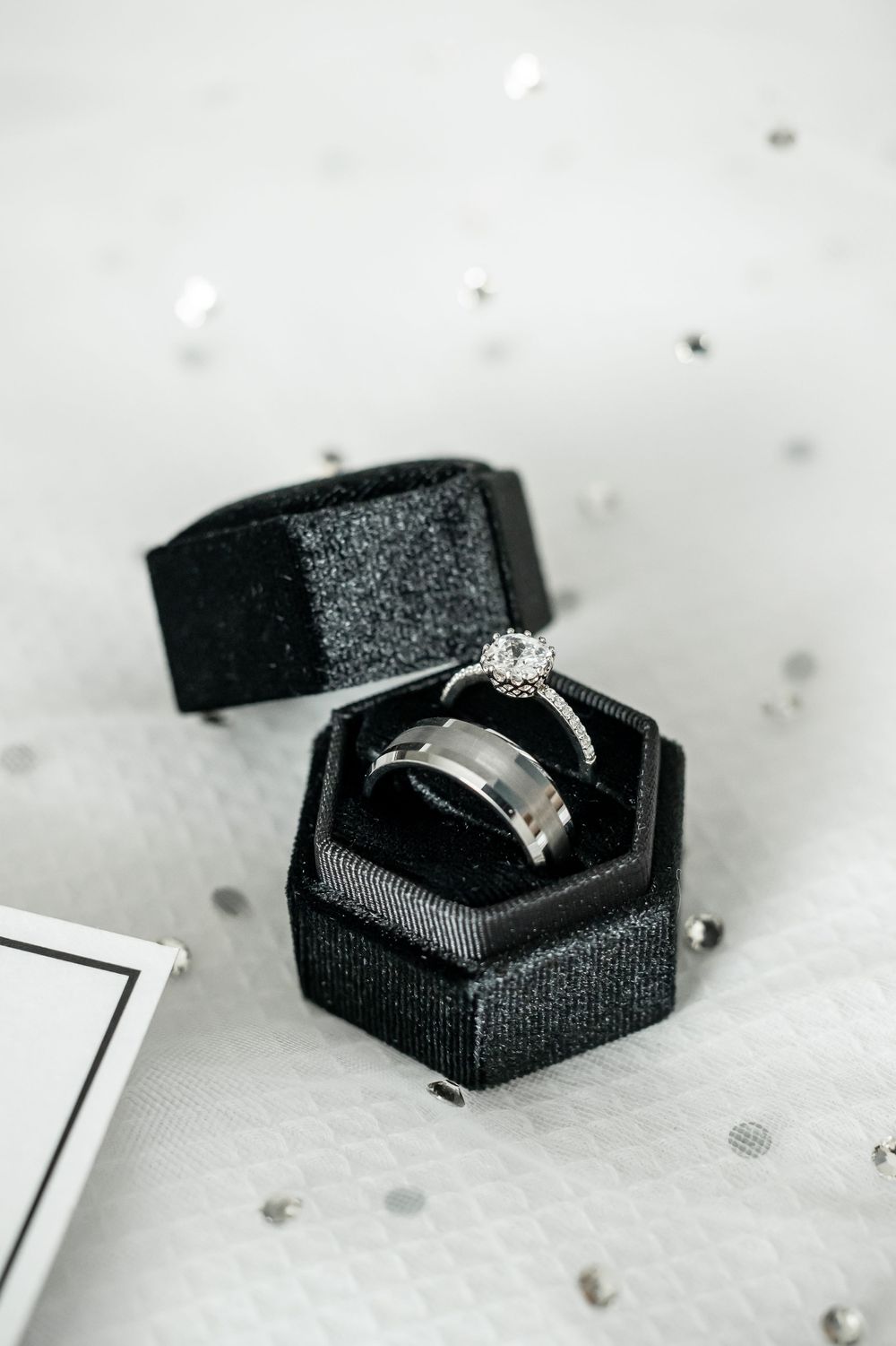 Diamond engagement ring and wedding band nestled in black velvet hexagonal ring box.