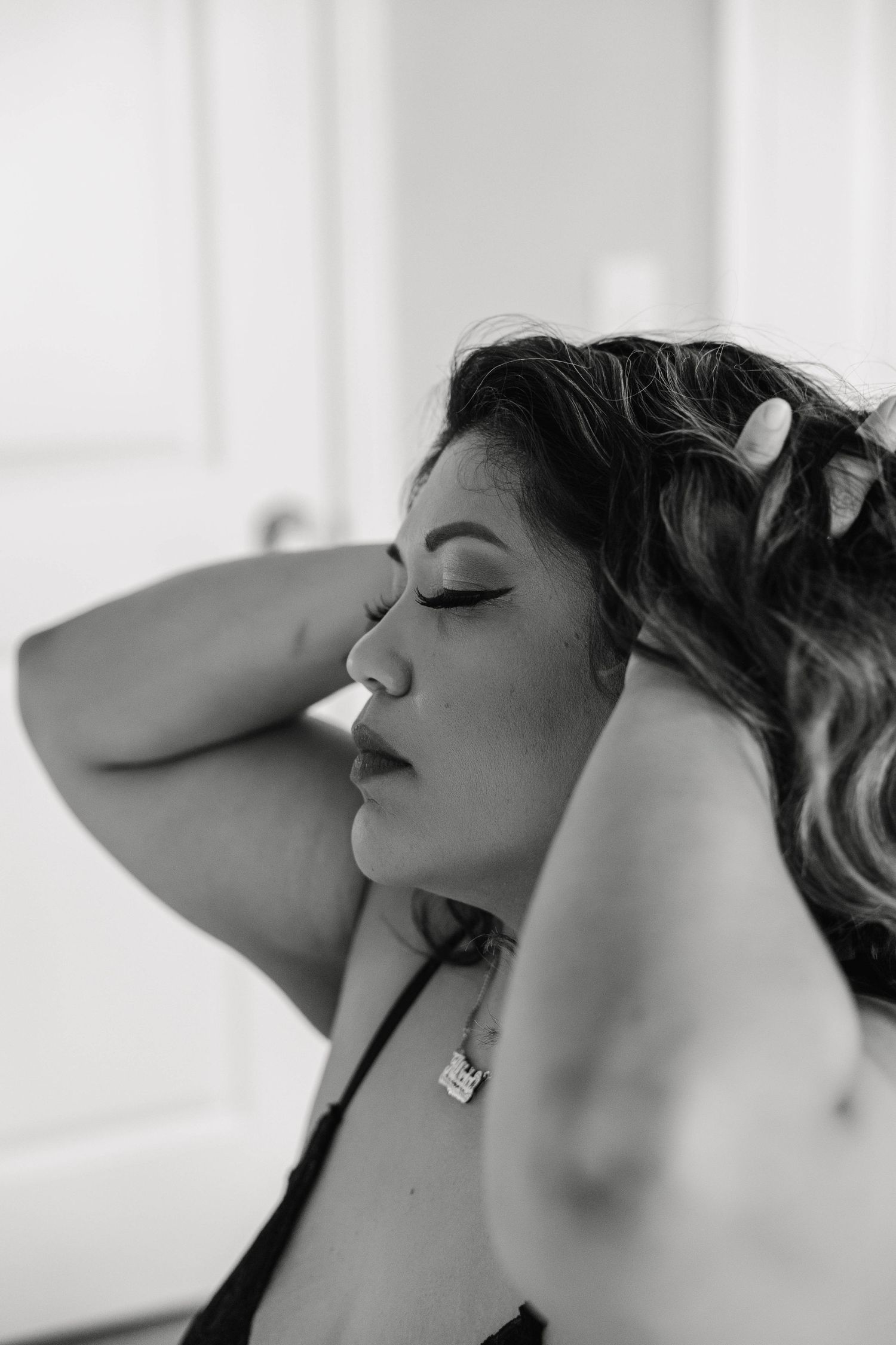 A woman running her hands through her hair in a private boudoir studio in Sarasota, by Sarasota boudoir photographer
