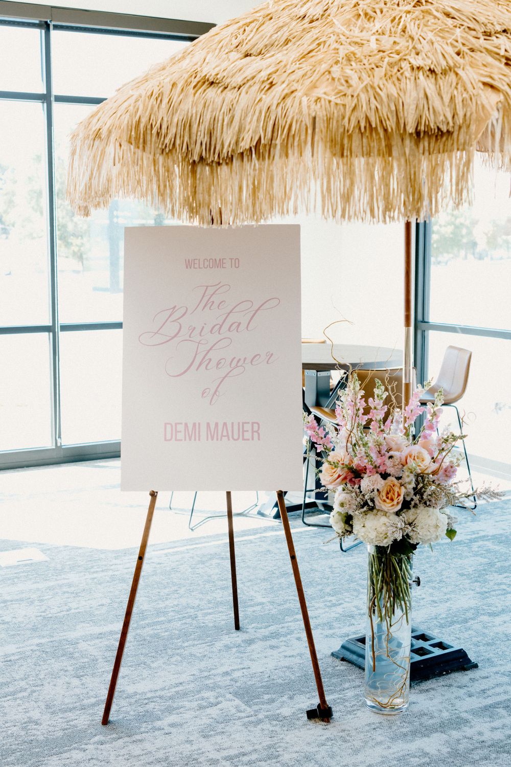 Tiki-style umbrella display with welcome signs and floral arrangements for a tropical themed event.