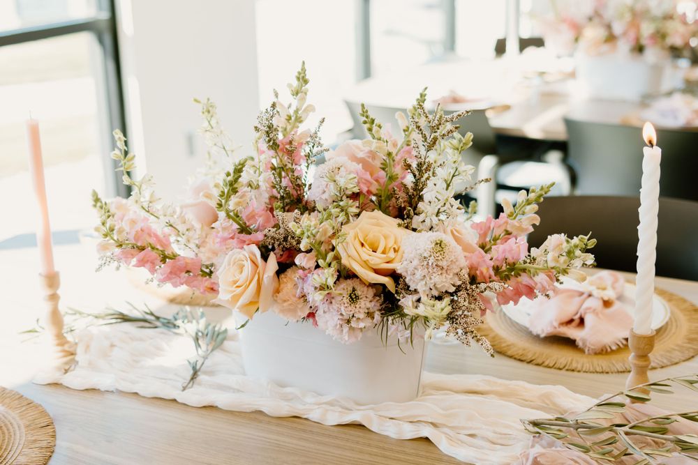 Delicate pink floral arrangements with white table settings and decorative elements.
