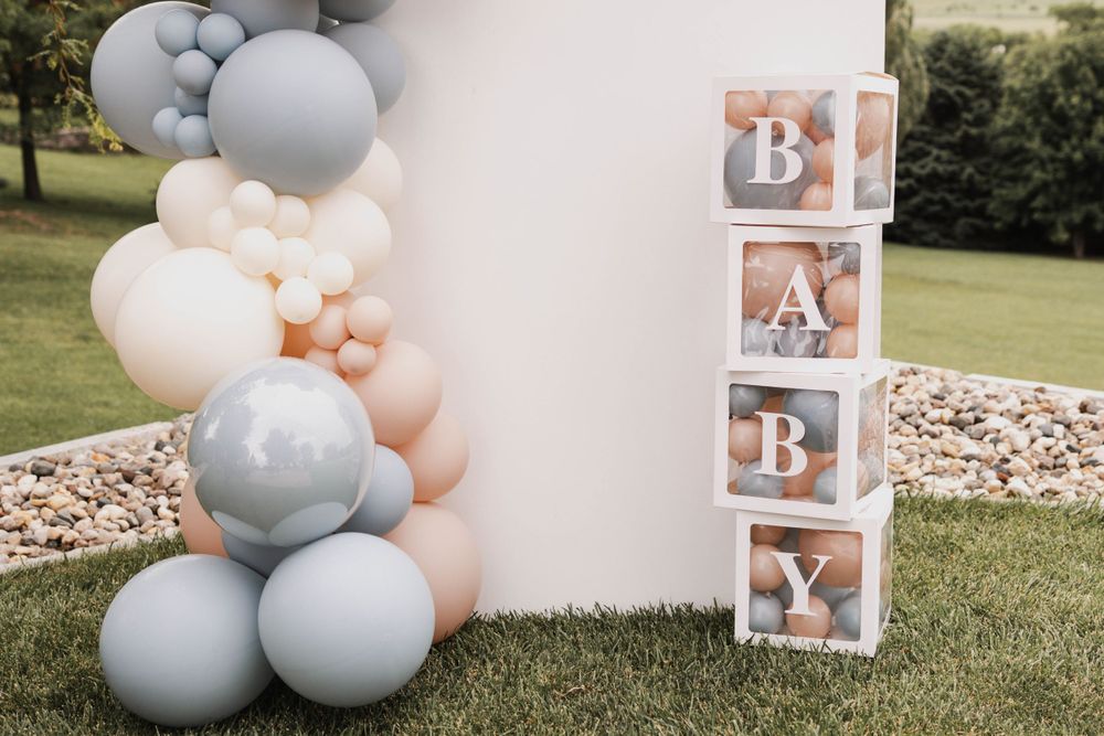 Gender reveal party setup with blue and pink balloon arch and photo display.