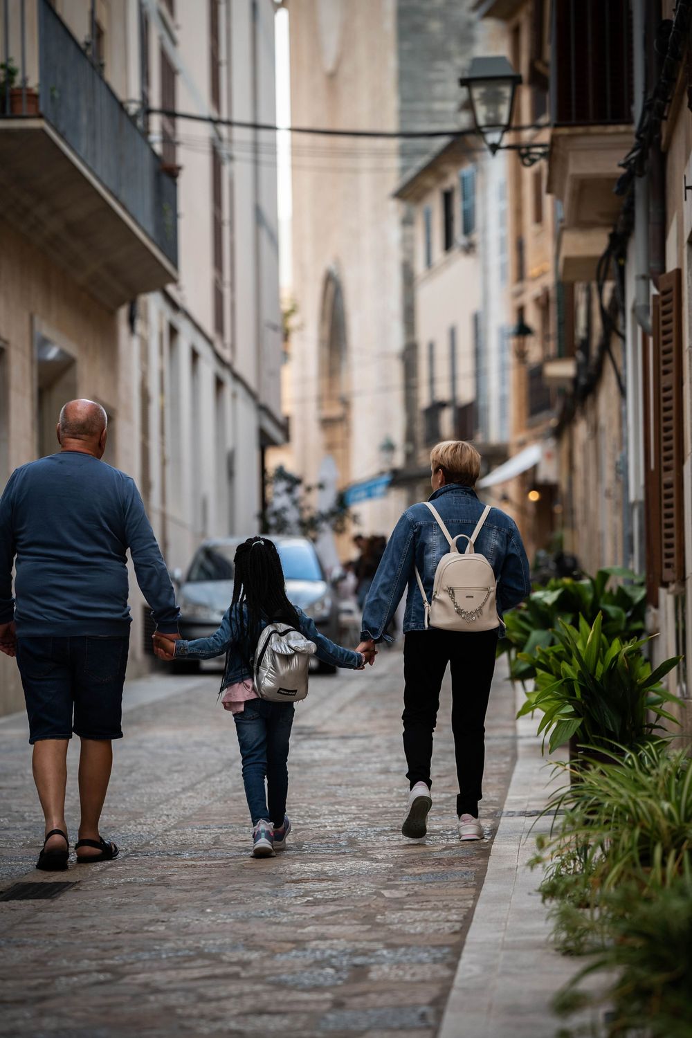 Three people walking together down a narrow European street with historic buildings.