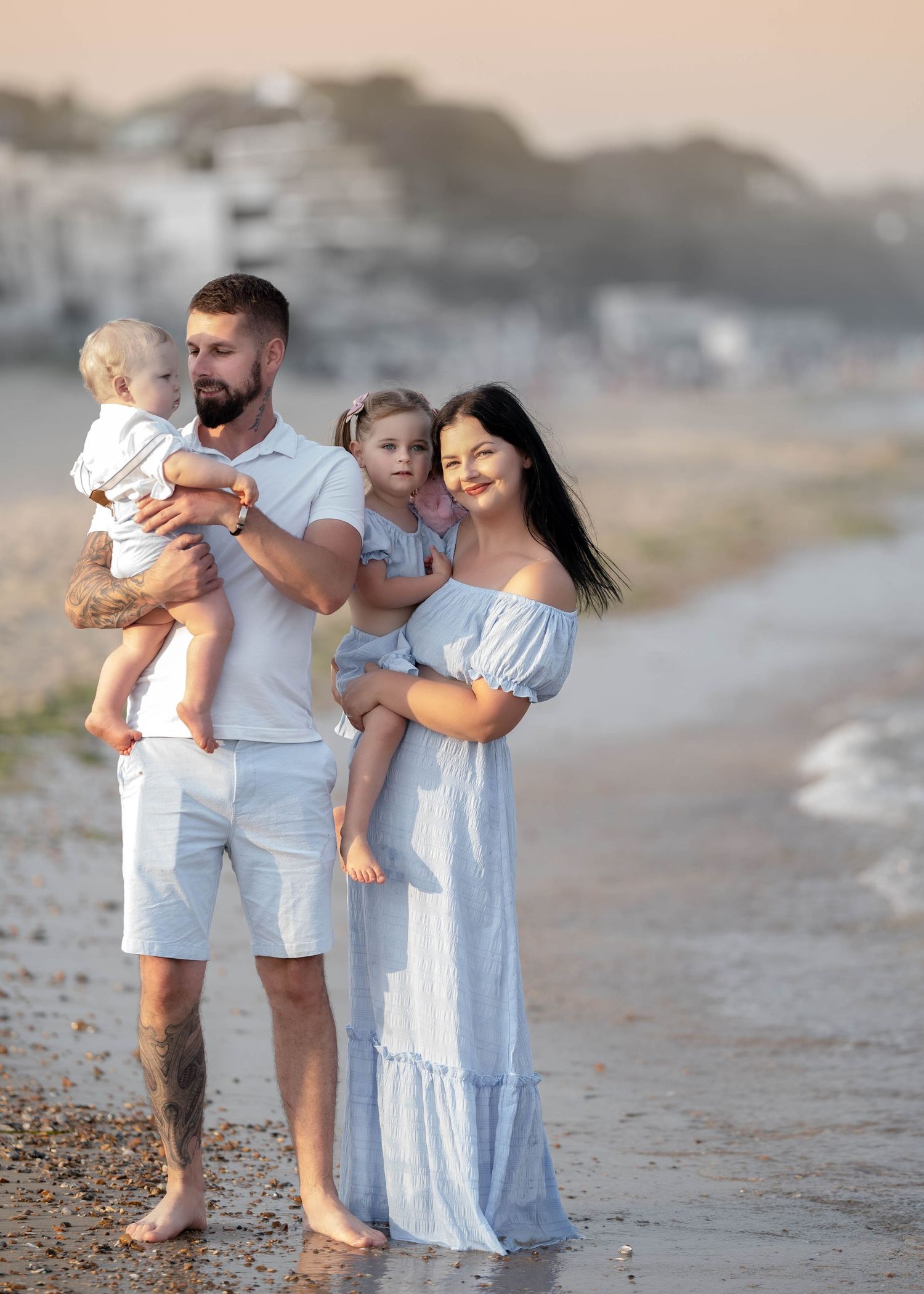 A family in white outfits walking together along a misty beach at sunset.