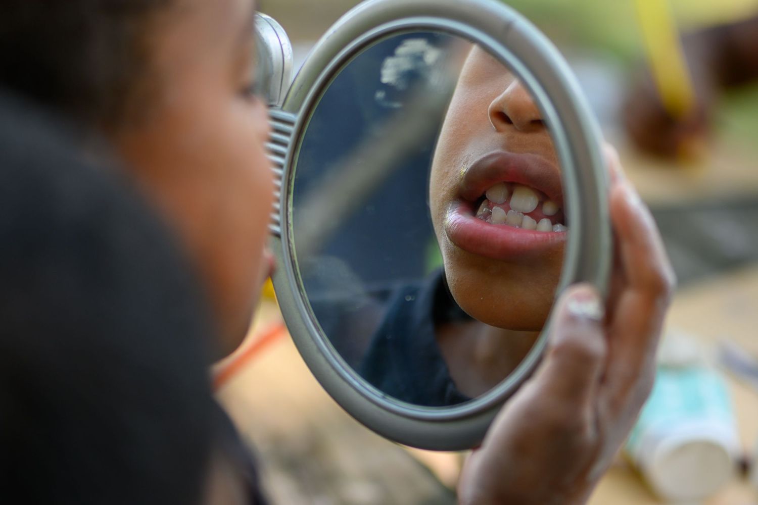 Close-up shot of a small mirror reflecting a joyful smile.
