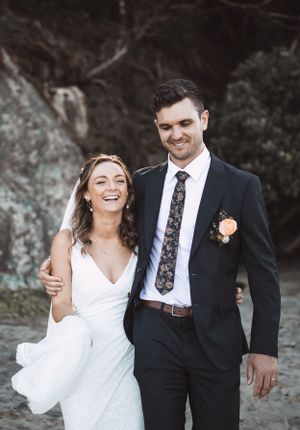 A joyful wedding couple sharing a candid moment against a rocky backdrop.