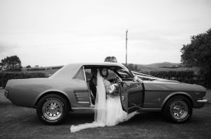 Vintage car silhouetted against sunset during a wedding photoshoot.