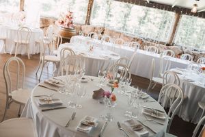 Elegant wedding reception venue with white table settings and modern bentwood chairs.