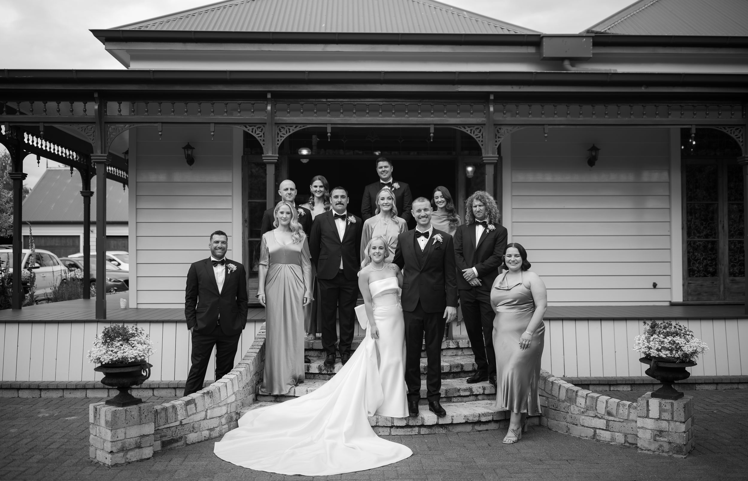 Wedding party poses in front of a classic white building with elegant columns and stone steps.
