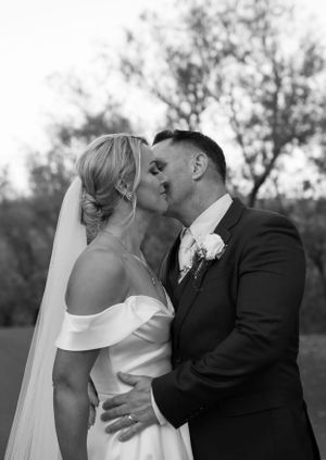 Black and white portrait of couple sharing romantic kiss outdoors.