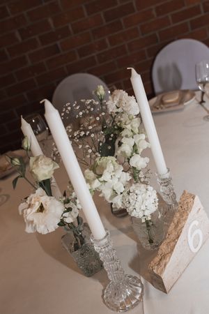 Elegant wedding centerpiece with white candles, lace details and delicate floral arrangements.