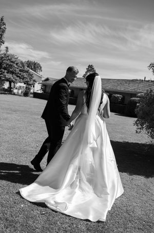 A black and white wedding photo sequence showing a couple walking together across a grassy field.