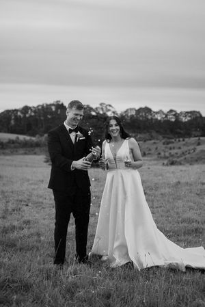 A romantic black and white wedding photo series showing a couple sharing tender moments in a scenic meadow.