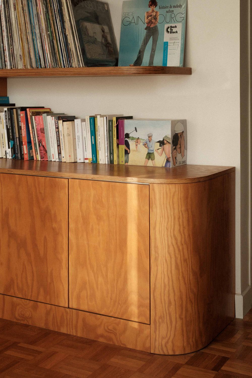 Vintage wooden cabinet with vinyl records displayed on shelf above.