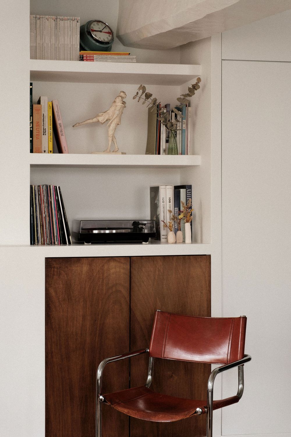 Vintage record player and decorative bird statue displayed on white built-in shelving.