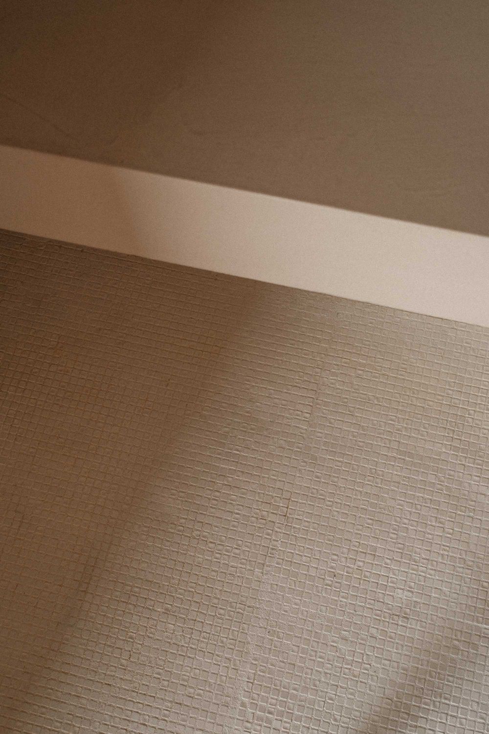 Abstract architectural detail showing textured beige wall and shadow play.