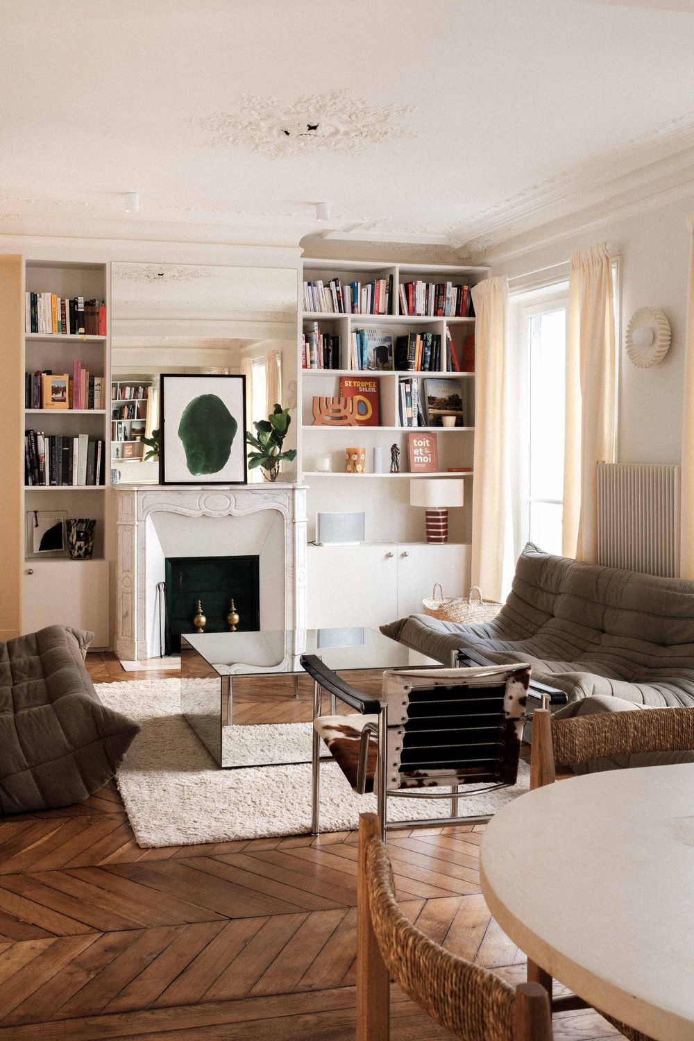 Modern living room with built-in bookshelves, fireplace and herringbone wood flooring.