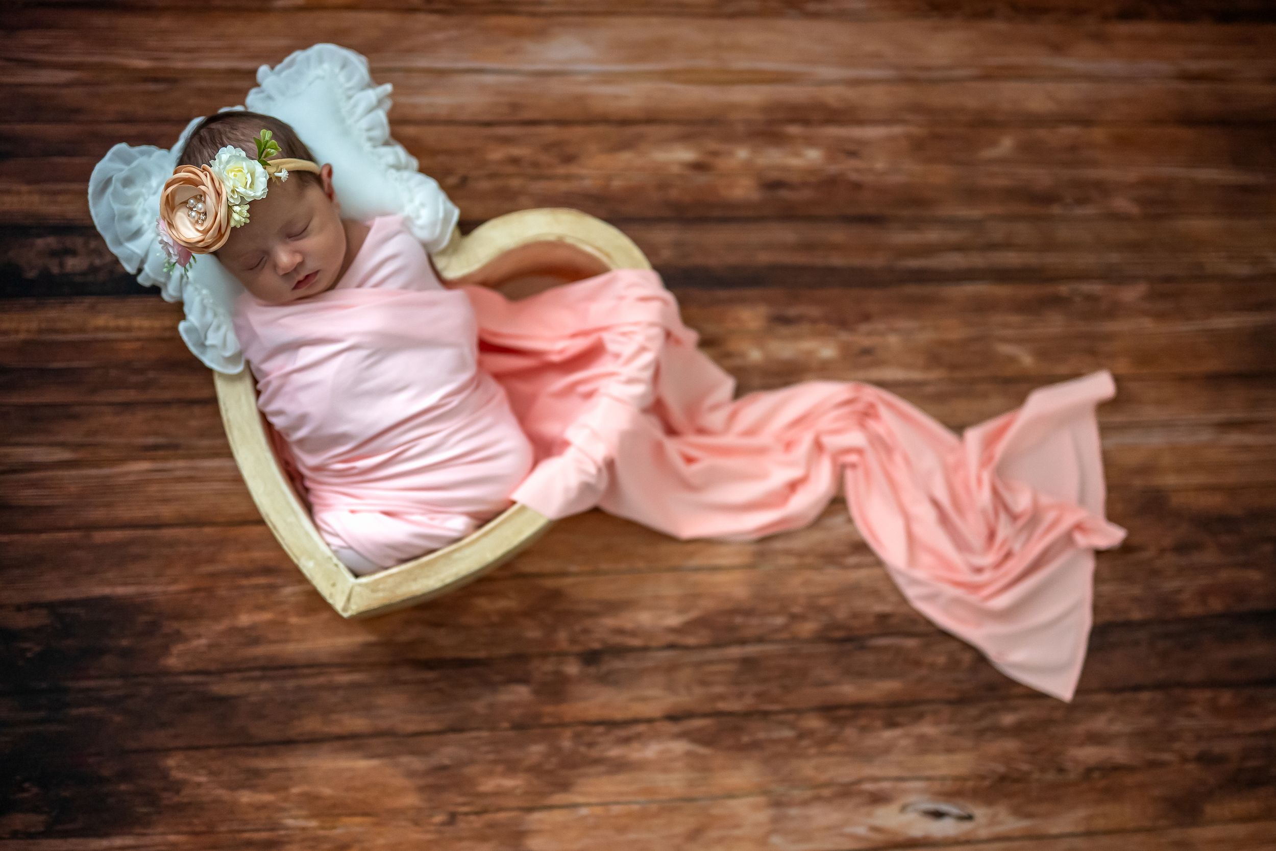 Pink and white baby swaddle blankets arranged on rustic wooden background.