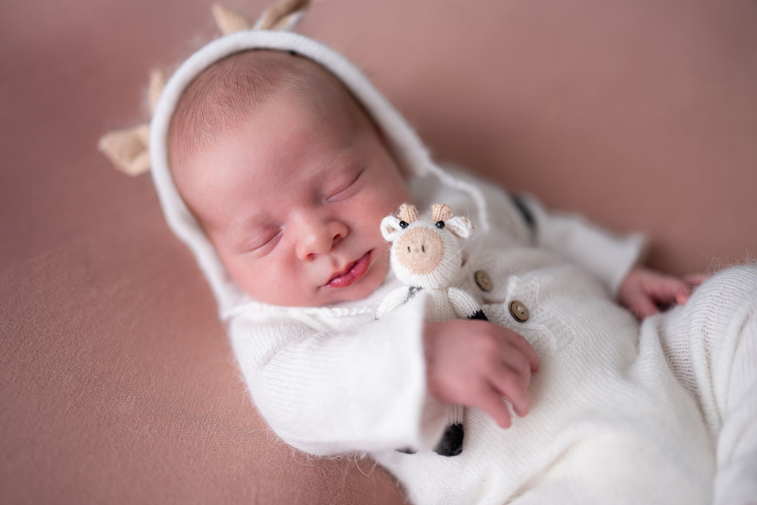 Collection of serene newborn photography showing sleeping baby in white wrap against soft pink backdrop.